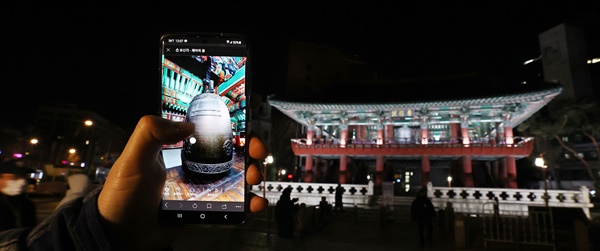 1일 새벽 서울 종로구 보신각 앞에서 시민이 스마트폰을 이용해 '제야의 종 가상현실(VR) 체험관'을 보고 있다. 이번 행사는 신종 코로나바이러스 감염증(코로나19) 확산 방지를 위해 67년만에 처음으로 비대면 방식으로 열렸다.