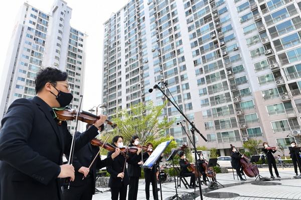 코로나19가 확산된 지난해 4월 수원의 한 공동주택 단지에서 오케스트라 공연이 열려 시민들이 베란다에서 관람하고 있다.