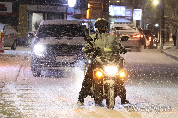 6일 오후 서울 성북구 월곡역 부근에서 폭설이 내리는 가운데, 퀵서비스 오토바이 운전자들이 두발로 균형을 잡으며 천천히 주행하고 있다.