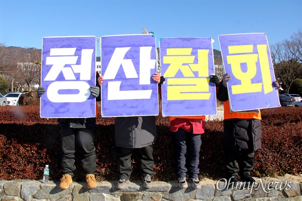 한국산연 노동자들이 경남도청 정문 앞에서 '청산철회' 손팻말을 들고 서 있다.