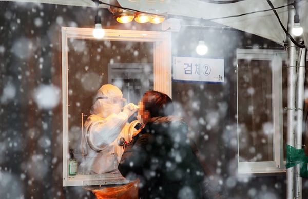 눈이 내린 12일 오후 서울역 광장에 마련된 코로나19 임시 선별검사소에서 시민들이 검사를 받고 있다.