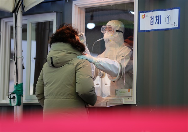 12일 오전 서울역 광장에 마련된 코로나19 임시 선별검사소에서 의료진이 검체채취를 하고 있다.