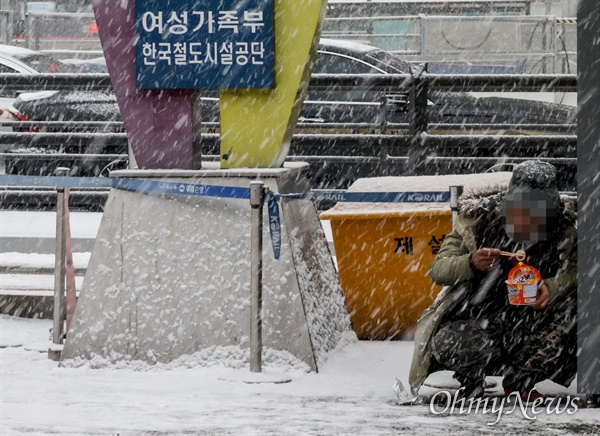 연일 혹한의 추위에 함박눈까지 내리는 12일 오후 서울 용산구 서울역광장에서 거리홈리스가 라면으로 끼니를 때우고 있다.