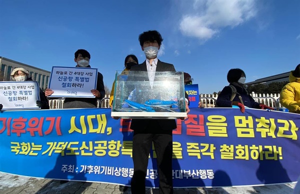 기후위기비상행동이 17일 국회 앞에서 가덕도 신공항 특별법 즉각 철회를 촉구하는 퍼포먼스를 펼치고 있다.