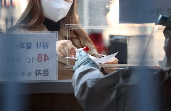 2월 27일 오전 서울역에 설치된 임시선별진료소에서 한 시민이 코로나19 검사를 받은 후 검체를 제출하고 있다.