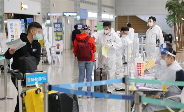 코로나19 신규 확진자 수가 이틀 연속 400명대를 기록한 4일 오전 인천국제공항 제2여객터미널에서 해외입국자들가 방역 관계자의 안내를 받고 있다.