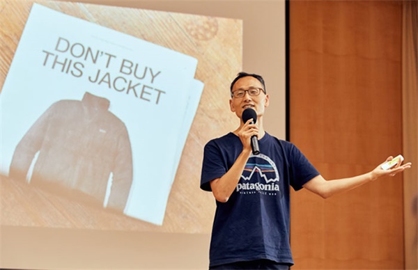 서진석 팀장이 파타고니아 티셔츠를 입고 행동주의 기업에 대해 강의하는 모습. 그의 뒤로 파타고니아의 유명한 카피 '이 재킷을 사지 마세요'가 보인다.