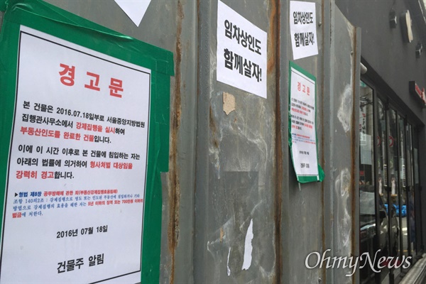 2016년 7월 17일 법원의 강제집행이 진행된 서울 신사동 가로수길의 한  건물 앞에 건물주의 경고문이 붙어 있다. 그 옆에는 맘편히장사하고픈상인모임(맘상모)에서 '임차상인도 함께 살자'란 표어를 붙였다.