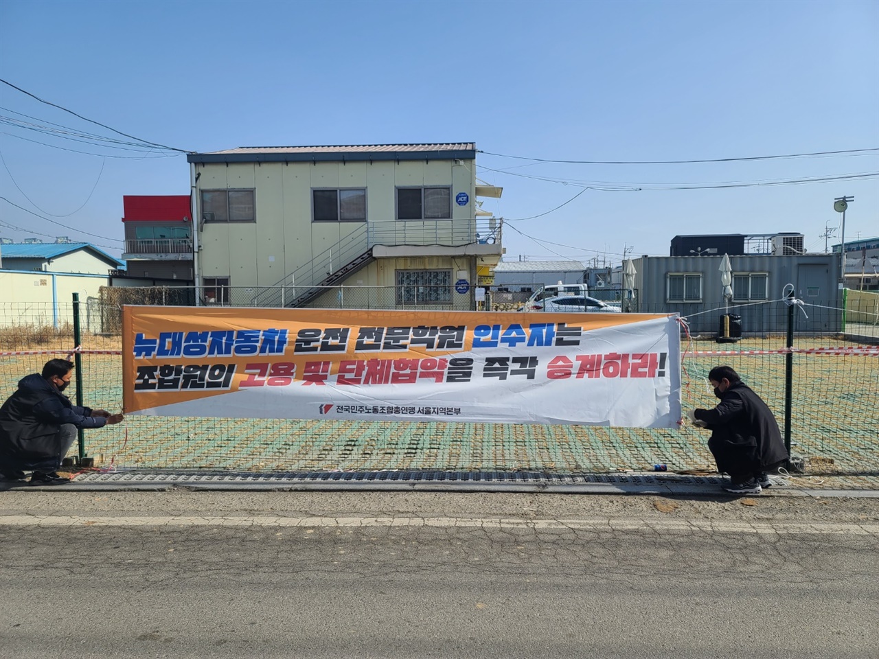  해고된 뉴대성자동차운전전문학원 기능강사들이 '호수자동차운전전문학원'으로 재개원이 임박한 학원 앞에 고용 및 단체협약 승계를 요구하는 현수막을 내걸고 있다. 