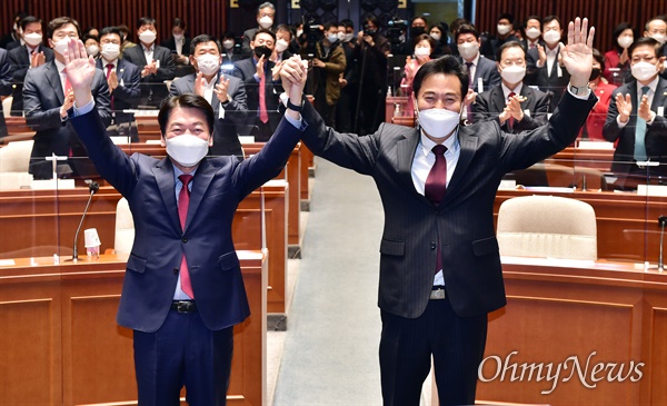  오세훈 국민의힘 서울시장 후보와 안철수 공동선거대책위원장이 24일 국회에서 열린 의원총회에서 손을 들어 인사하고 있다.