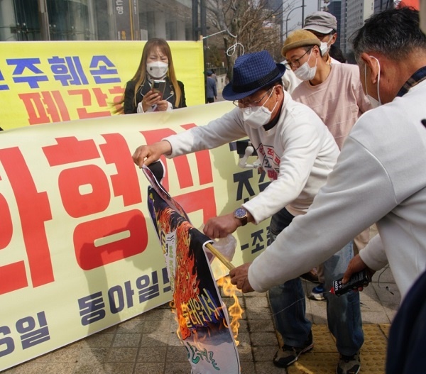 기자회견 참석자들이 박재동 화백이 그린 '불타는 조중동' 작품에 불을 점화하고 있다.