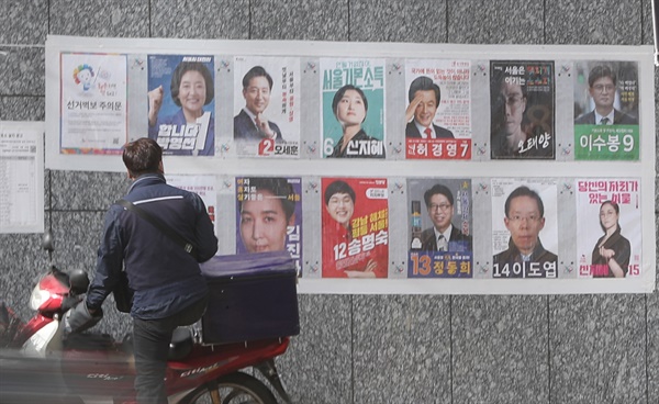 4.7 서울시장 보궐선거 사전투표를 나흘 앞둔 2021년 3월 29일 오전 시민들이 서울 중구 명동 입구에 부착된 선거벽보 앞을 지나고 있다.