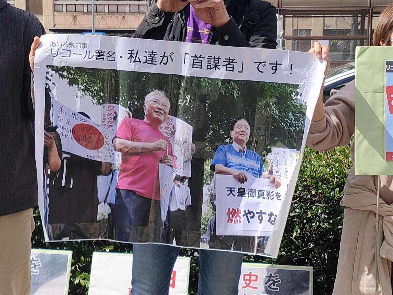 나고야 시청 앞에서 가와무라 시장과 다카스 원장이 함께 주민소환 투표 운동을 벌이는 사진을 들고 항의하는 시민