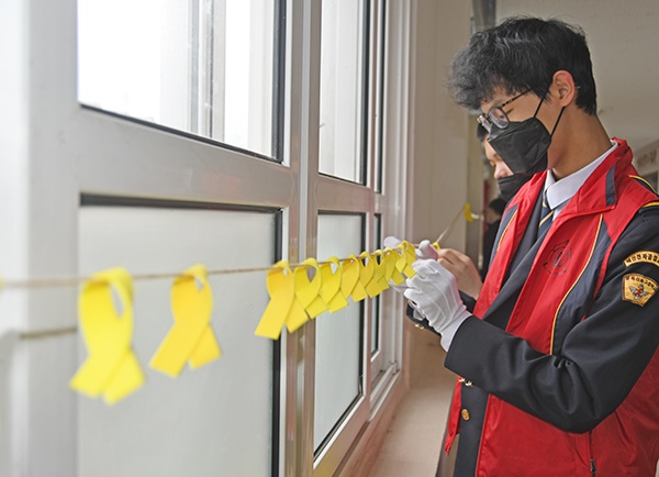 학생들이 복도 창문 앞에 노란리본을 달고 있다.