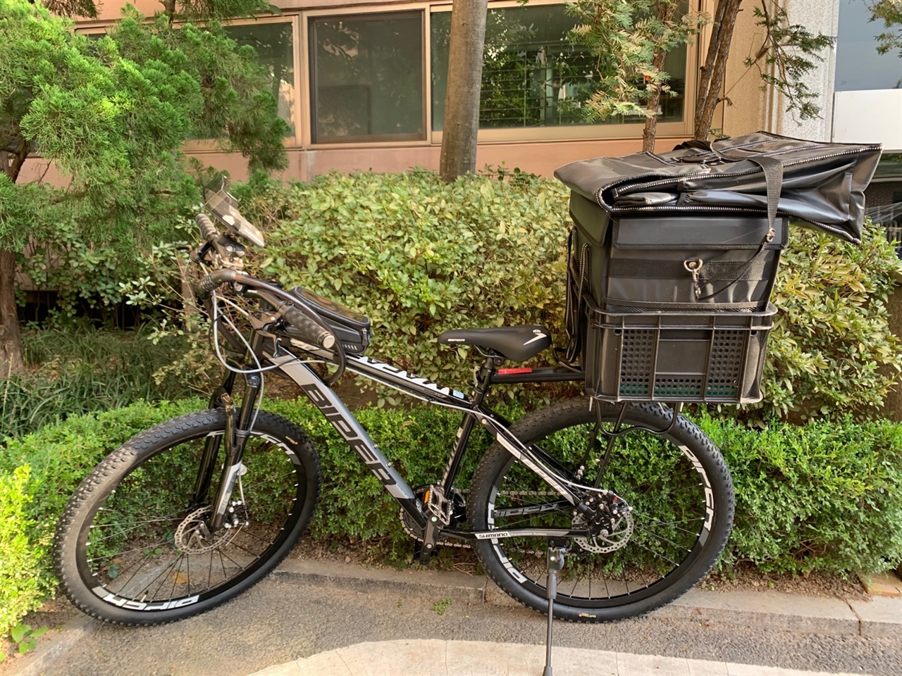 자전거 뒤에 짐받이를 달고 음식 담을 수 있는 배달 가방을 실었다. 