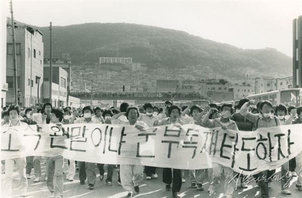 1987년 6월 항쟁 당시인 6월 10일 부산 충무동 로터리 시위. 변호사 시절 노무현 전 대통령이 '고문 살인 은폐조작 왠말이냐 군부독재 타도하자'라는 플래카드를 펼친 시위대열 앞에 서 있다