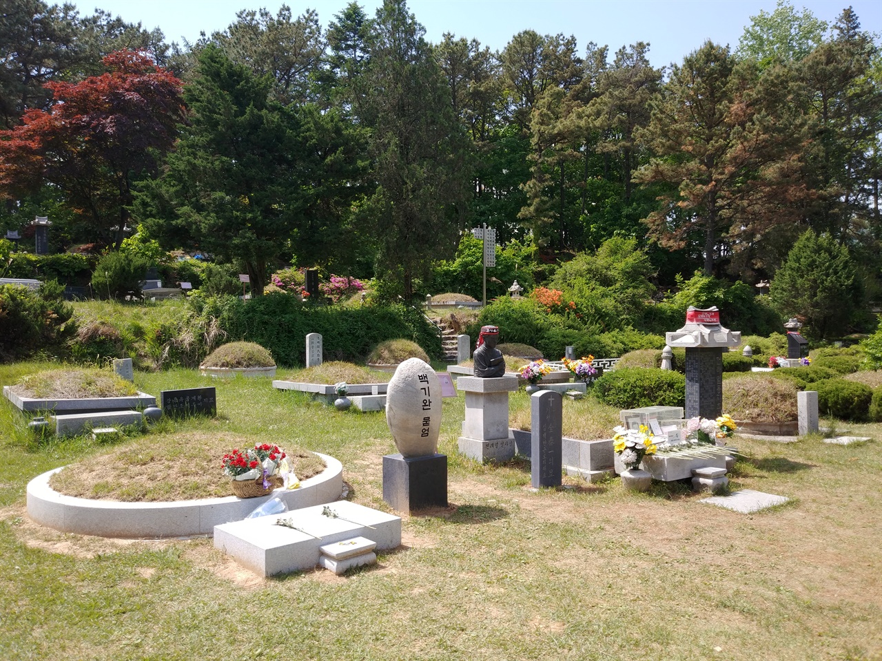 모란공원 민족민주열사 묘역의 중심에는 전태일 열사와 백기완 선생의 묘소가 나란히 자리하고 있다. 그 너머로 '중대재해기업처벌법' 제정의 도화선이 된 김용균님의 묘소가 보인다.