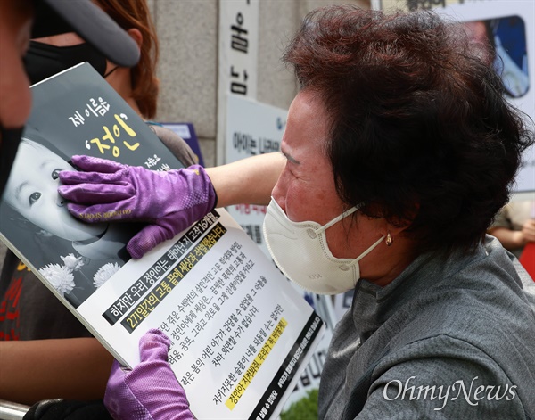 14일 오후 16개월된 입양아 정인이를 학대해 숨지게 한 양부모에 대한 1심 선고가 열린 서울남부지법앞에서 한 시민이 정인이 사진을 어루만지며 눈물을 흘리고 있다.