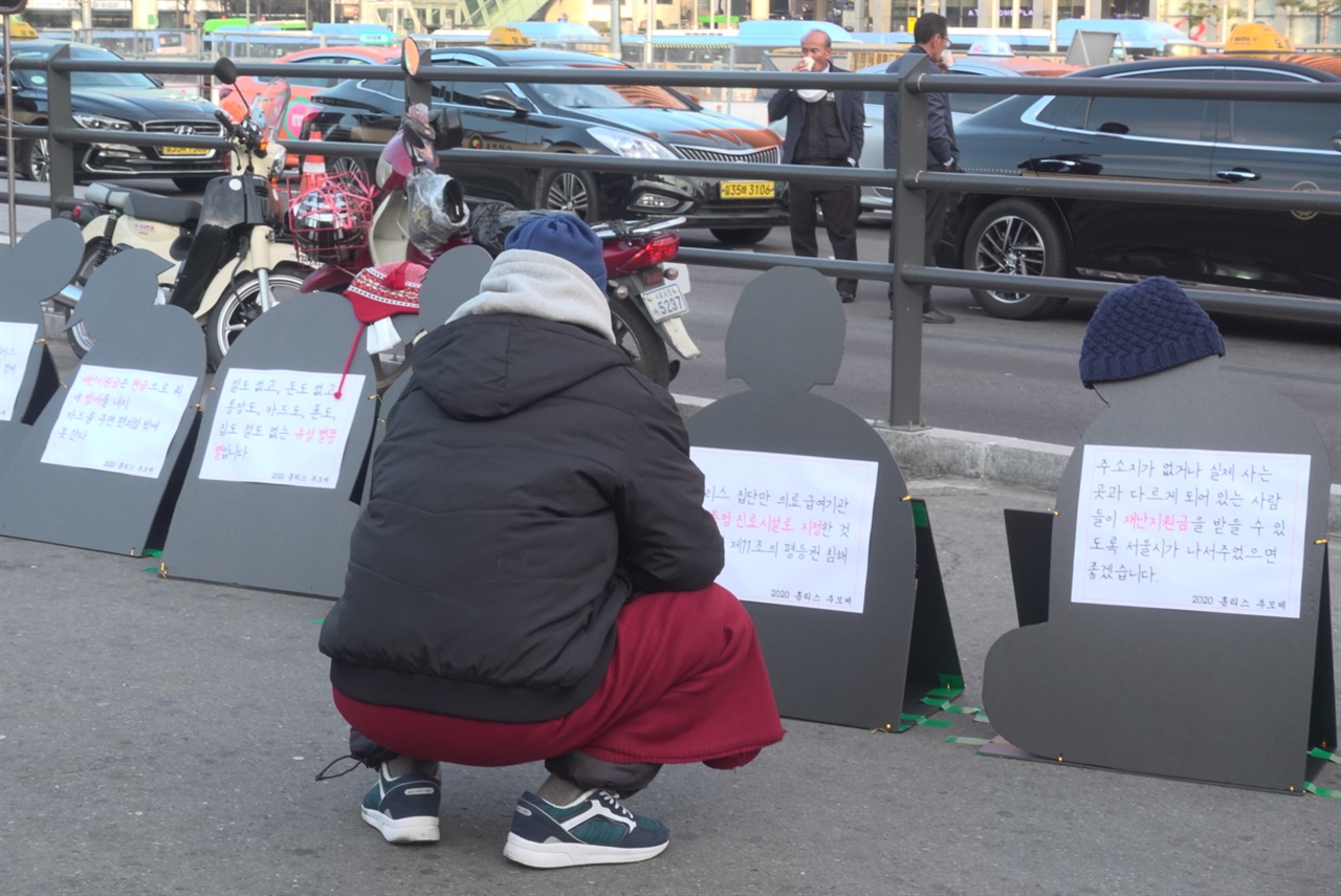 2020년 12월 21일, 동짓날. 이주민 홈리스 L씨가 서울역 광장에 설치된 '홈리스추모제' 선전물을 바라보고 있다.