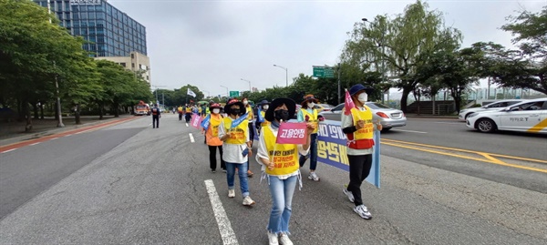 고용안정’과 ‘처우개선’이 써 있는 깃발을 들고 도보행진 하고 있는 한국가스공사 비정규직 노동자들