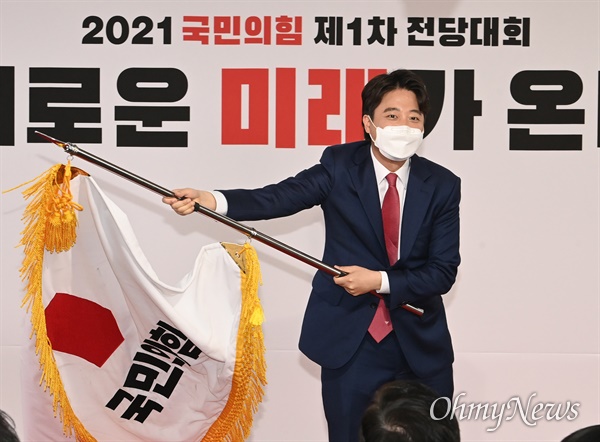 2021년 6월 11일 국민의힘의 새 얼굴로 선출된 이준석 당대표가 서울 여의도 국민의힘 중앙당사에서 열린 제1차 전당대회에서 당기를 흔들고 있다.