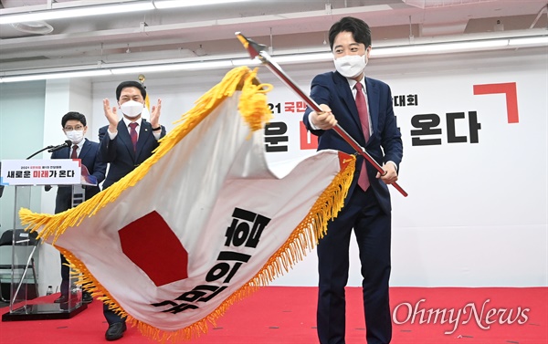 국민의힘 이준석 신임 당대표가 11일 서울 여의도 국민의힘 중앙당사에서 열린 제1차 전당대회에서 당기를 흔들고 있다.