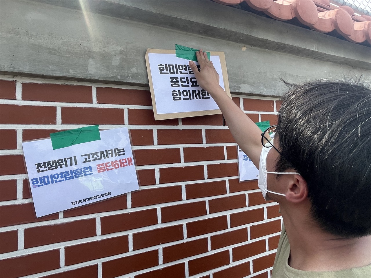 집회 참가자들이 주한미군기지 벽면에 구호가 적힌 피켓과 항의서한문을 붙이고 있다.
