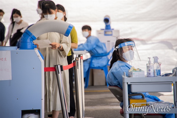 지난 16일 오후 서울역에 설치된 선별검사소에서 의료진이 냉풍기에 열을 식히고 있다.
