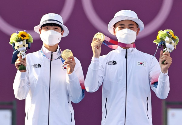  양궁 국가대표 김제덕과 안산이 24일 일본 도쿄 유메노시마 공원 양궁장에서 열린 도쿄올림픽 혼성 결승전에서 금메달을 획득한 후 메달을 보이고 있다.