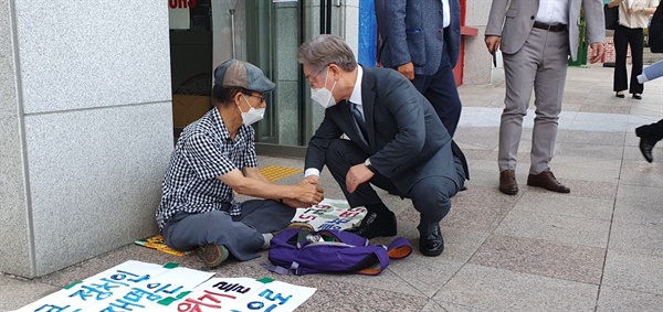  이재명 경기지사가 31일 오후 더불어민주당 경남도당 앞에서 박종권 경남기후위기비상행동 공동대표를 만나 손을 잡고 이야기를 나누고 있다