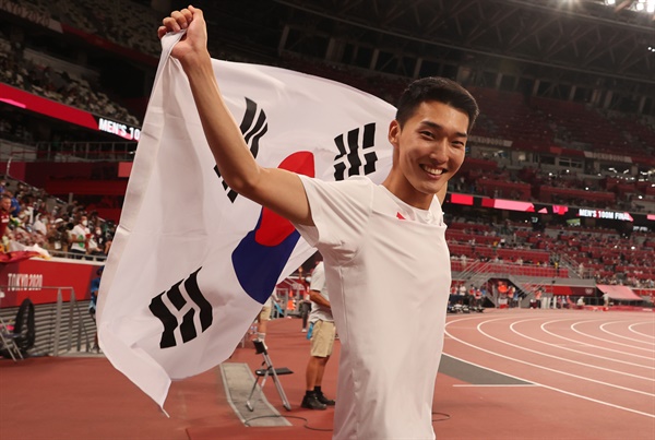 1일 도쿄올림픽 남자 높이뛰기에서 2m35 한국신기록을 세우며 4위를 차지한 우상혁이 도쿄 올림픽스타디움에서 경기 종료 후 태극기를 펼치며 기뻐하고 있다.