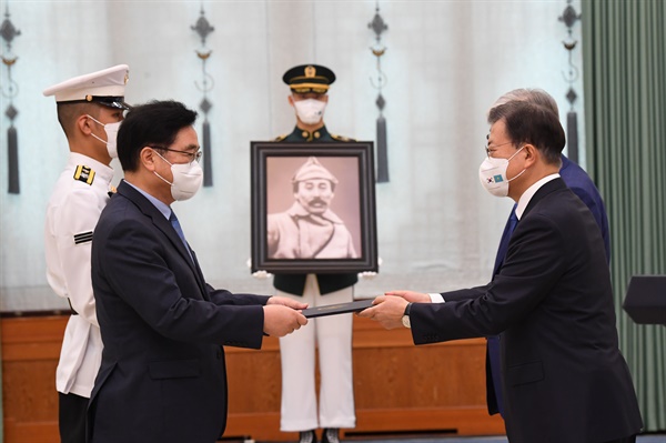 문재인 대통령이 17일 청와대에서 열린 고 홍범도 장군 훈장 추서식에서 홍범도장군기념사업회 우원식 이사장에게 건국훈장 대한민국장을 추서하고 의장병이 들고 있는 추서판에 부장을 걸어주고 있다. 