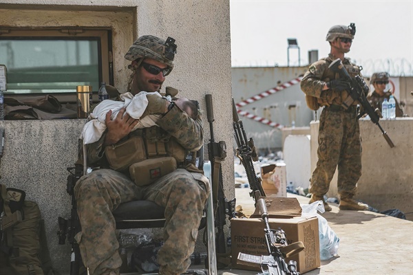 20일(현지시각) 아프가니스탄 수도 카불의 하미드 카르자이 국제공항을 경비하는 미국 해병대원이 아기를 품에 안고 달래고 있다. 