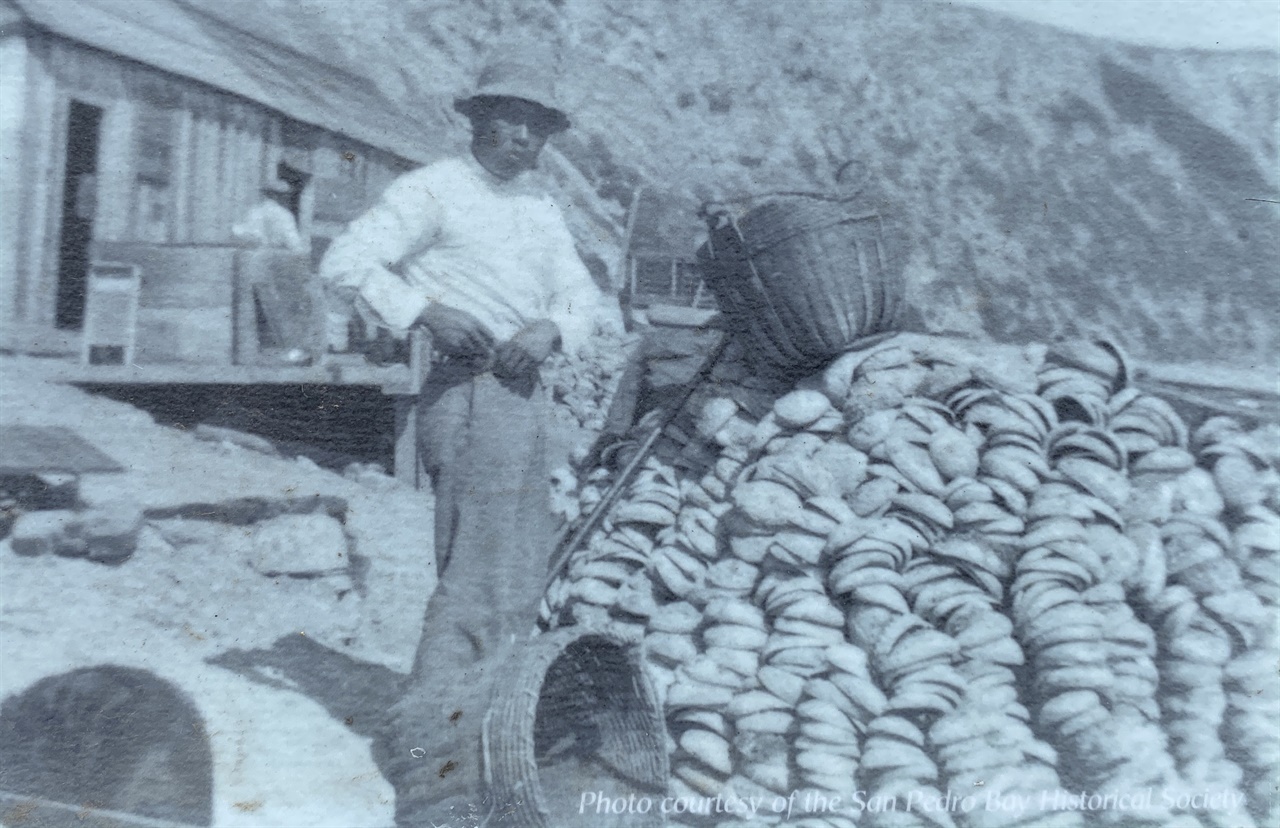 일본계 미국인 어부가 전복 껍데기 더미 앞에 서 있다.