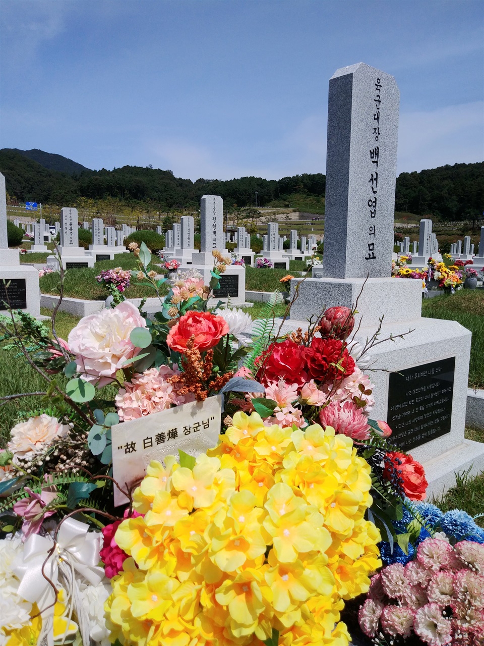 백선엽 묘소 앞에는 화환과 울긋불긋한 꽃다발이 많았다. '고 백선엽 장군님 사랑합니다'는 팻말이 눈에 띈다.