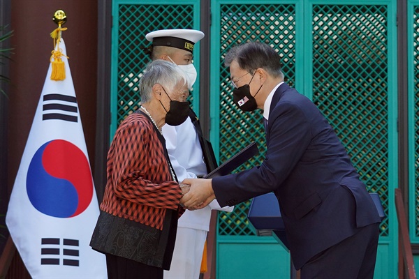  문재인 대통령이 22일(현지시각) 미국 하와이대 한국학 연구소에서 열린 독립유공자 훈장 추서식에서 독립유공자 김노디 지사 후손 위니프레드 리 남바 옹에게 애국장을 수여한 뒤 두 손을 맞잡고 있다. 