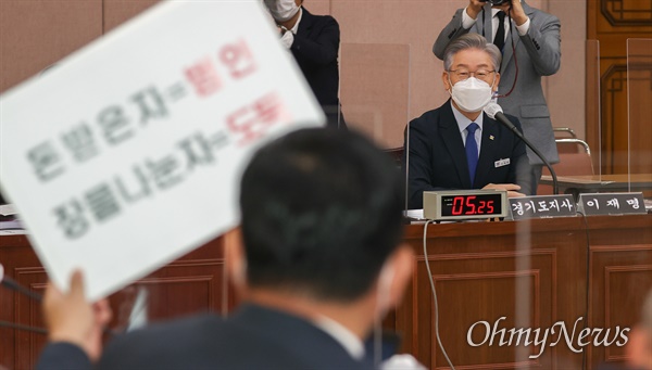  이재명 경기도지사가 20일 경기도 수원시 팔달구 경기도청에서 열린 국회 국토교통위원회의 경기도청에 대한 국정감사에서 국민의힘 박성민 의원이 질의 도중 피켓을 들어보이자 바라보고 있다.