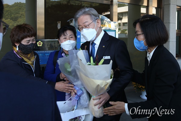  더불어민주당 대선 후보인 이재명 경기지사가 25일 오후 경기도 수원시 경기도의회에서 열린 감사패 수여식에 입장하는 도중 지지자들에게 꽃다발을 받고 있다.