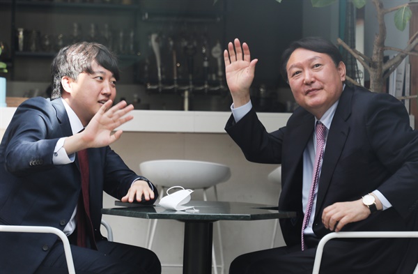 국민의힘 이준석 대표(왼쪽)와 윤석열 대선 후보가 6일 오후 서울 마포구 한 음식점에서 오찬 회동 중 창밖에 모인 시민들을 향해 손을 흔들고 있다. 