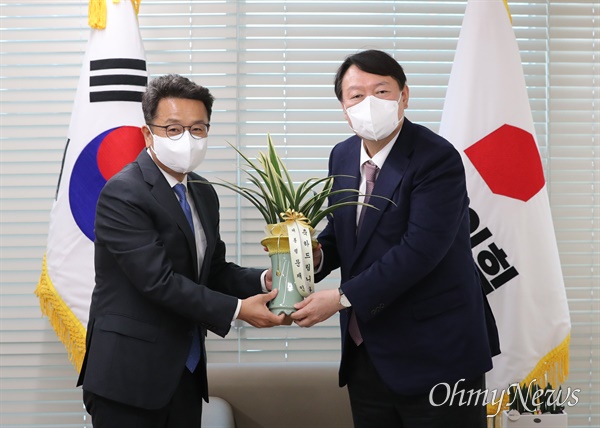 국민의힘 윤석열 대선 후보가 15일 오후 서울 영등포 국민의힘 당사에서 이철희 청와대 정무수석으로부터 문재인 대통령의 축하 난을 전달받고 있다.