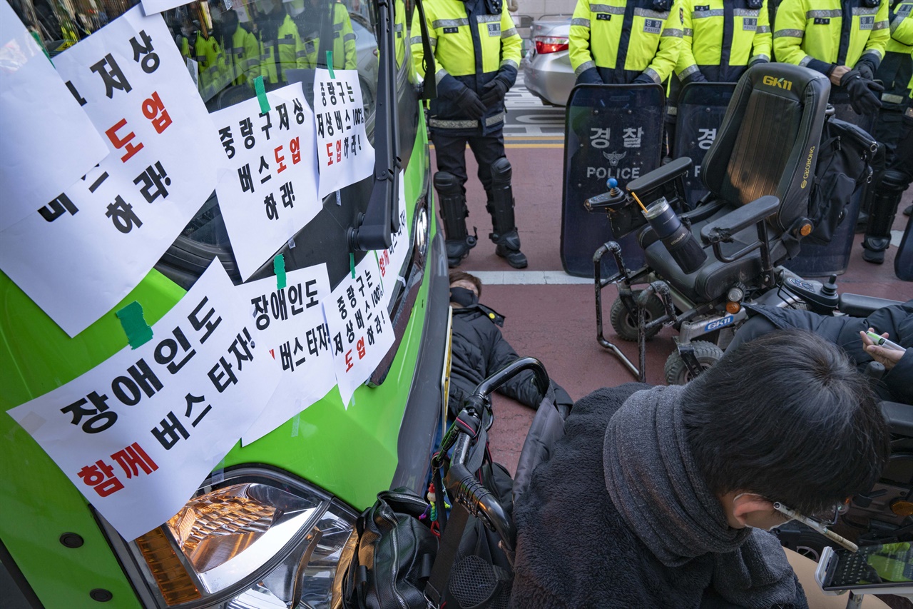 '서울시 장애인 이동권 선언' 완전이행 촉구 집회에서 집회 참여자가 저상버스의 도입을 촉구하며 버스 아래 누워 버스의 이동을 막고 있다.