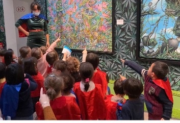 잔디 미술관에 있는 작품을 보며, 큐레이터는 아이들에게 그림 속에 숨은 그림 찾기 퀴즈를 냈다. 아이들은 각자 자신이 찾은 곳을 손으로 가리키고 있다. 