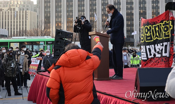 이성만 더불어민주당 의원이 22일 오후 서울 종로구 광화문 시민열린마당에서 열린 소상공인, 자영업자 생존권 결의대회에 참석해 단상에 나와 발언하자, 한 참석자가 “내려가라”고 항의하고 있다.