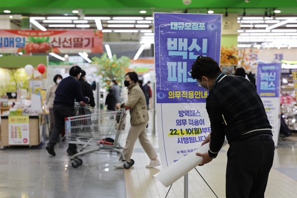 법원이 서울 마트·백화점에 대해 방역패스 효력 정지를 결정한 14일 오후 서울 서초구 양재동 농협하나로마트에서 관계자가 방역패스 안내문을 치우고 있다.