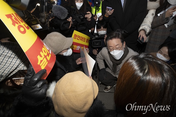 더불어민주당 이재명 대선 후보가 21일 서울 마포구 연남동 거리에서 열린 '걸어서 민심 속으로' 연남동 거리 걷기 행사에서 정인이 재판 관련 시민들을 만나 쪼그리고 앉아 이야기를 듣고 있다.
