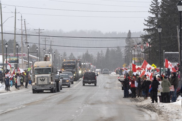 지난 26일 캐나다 온타리오주 선더베이 외곽의 카카베카 폭포에서 트럭과 차량 행렬이 지나가고 있다. 미국-캐나다 국경을 오가는 트럭 운전자들을 대상으로 한 '코로나 백신 의무 조치'에 반대하는는 시위대와 지지자들이 환호하고 있다. 
