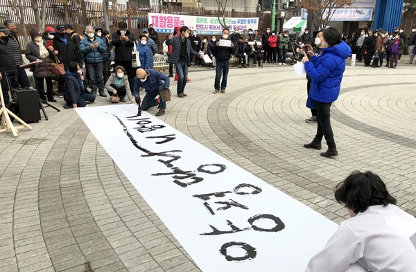 서예가 전기중씨가 마당극 도중 글쓰기를 하고 있다.