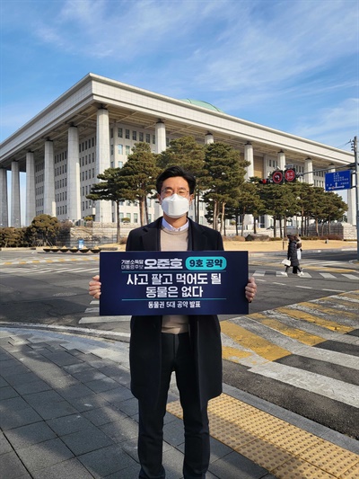 기본소득당 오준호 후보가 2월 9일 국회 앞에서 '사고 팔고 먹어도 될 동물은 없다' 피켓을 들고 있다.