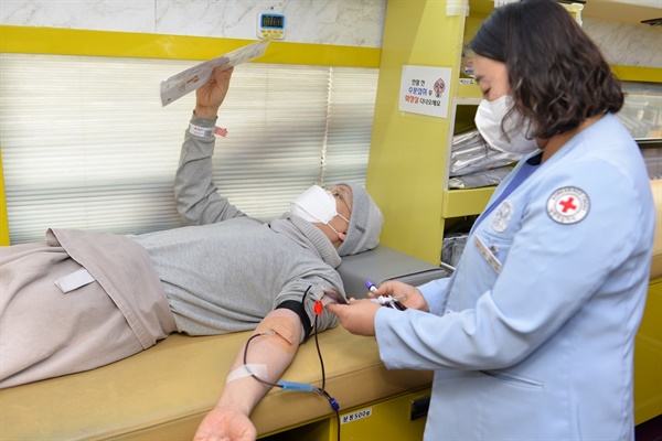 화엄사 스님이 헌혈을 하며 헌혈 안내문을 살펴보고 있다. 
