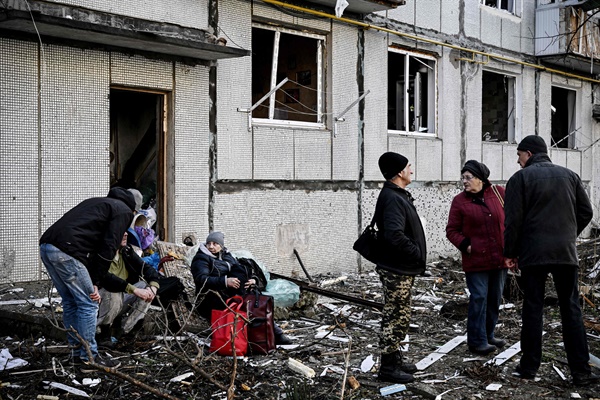 24일 우크라이나 동부 추귀브에서 포탄 공격을 받은 건물 주변에 사람들이 서 있다. 